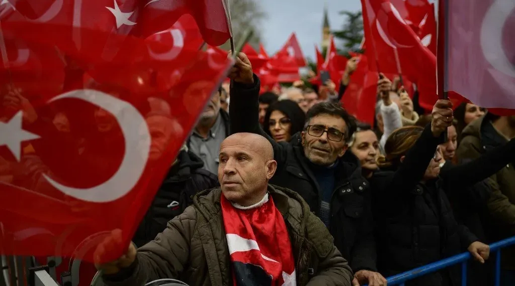 Supporters of Istanbul Mayor Ekrem Imamoglu wave national flags as they gather in front of the Istanbul Metropolitan Municipality during a protest in Istanbul on December 15, 2022, after a Turkish court sentenced him to more than two years jail and banned him from politics ahead of next year's presidential election. (Photo by Yasin AKGUL / AFP)